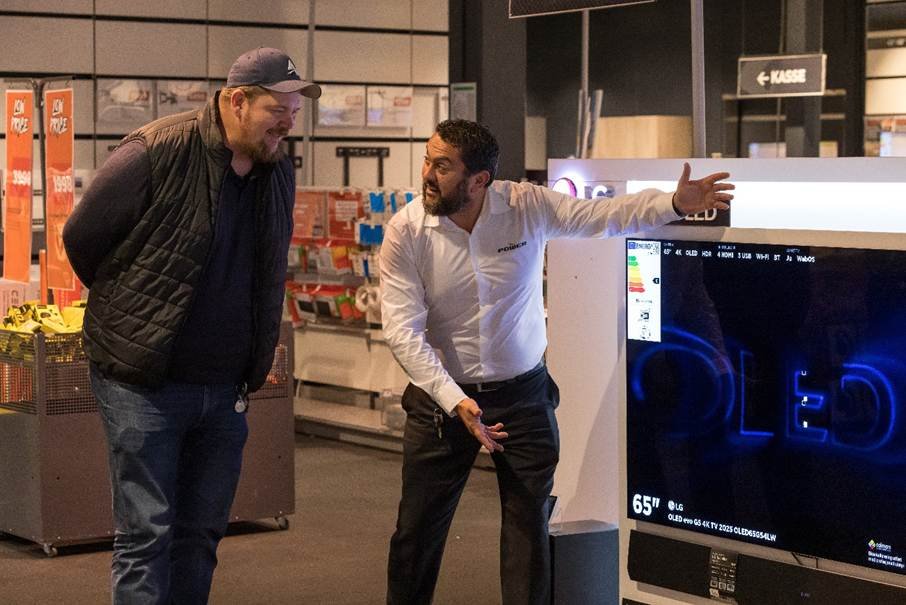 Stian Dagslott viser Patrick Walther Larsen et av de flotte fjernsynene Power har i butikken.